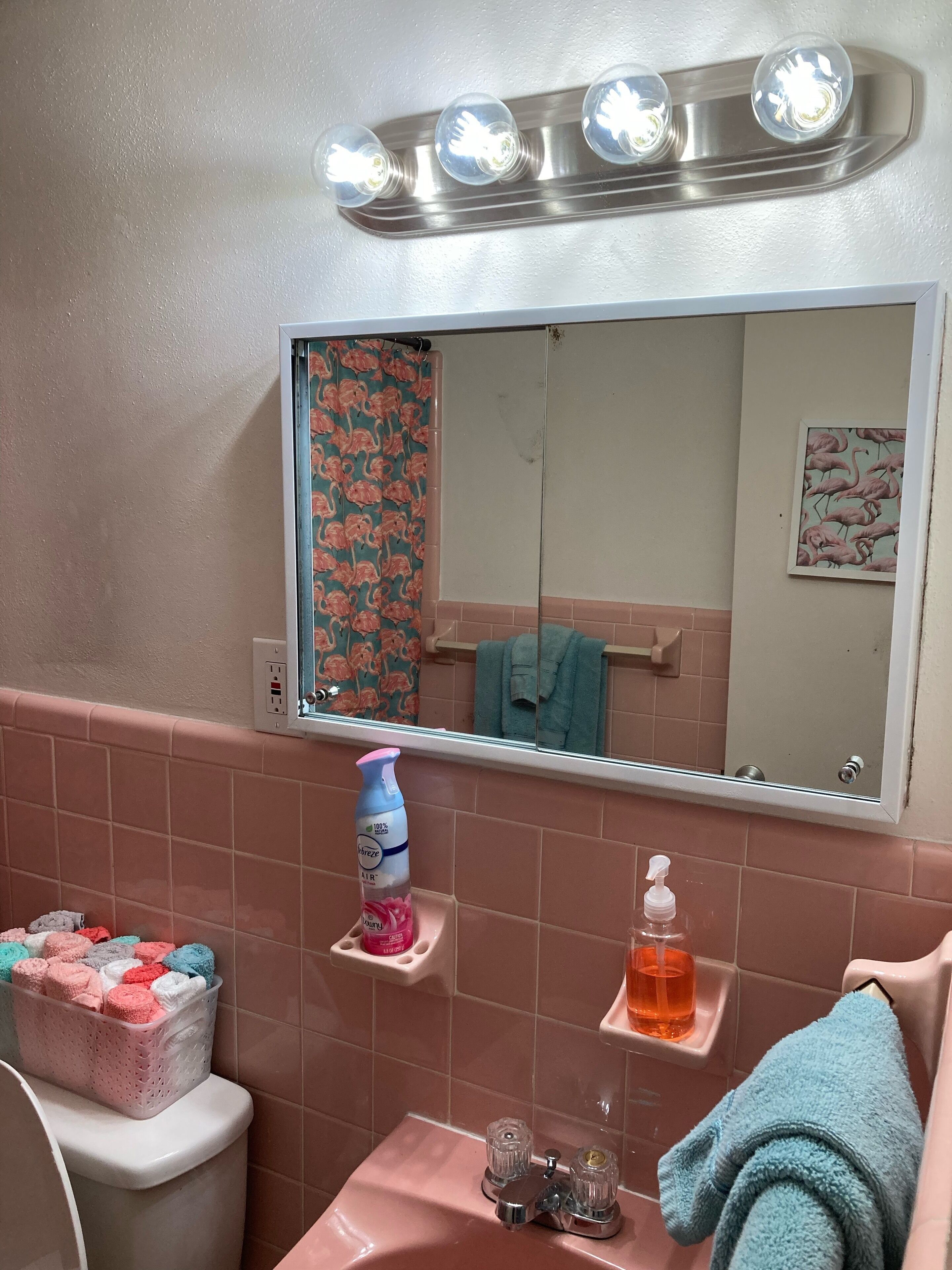 Une salle de bain comprenant un meuble-lavabo, un miroir, un luminaire, un porte-serviettes et des toilettes.