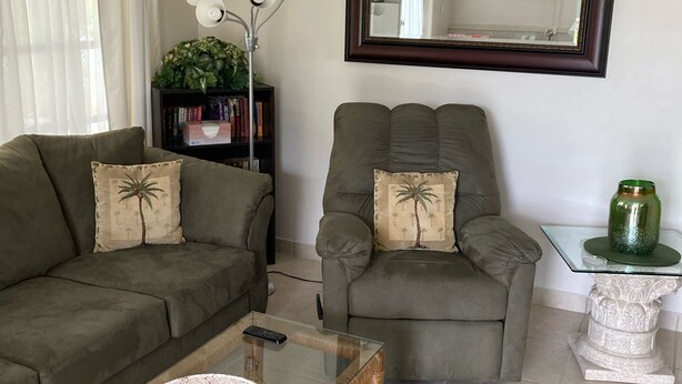 A living room with a sofa, armchair, glass coffee table, and a side table with a vase. - CHARLOTTE HARBOR BUNGALOW (Port Charlotte)