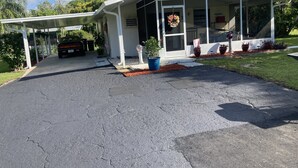 A single-story building with a covered porch, a driveway, and potted plants. - CHARLOTTE HARBOR BUNGALOW (Port Charlotte)