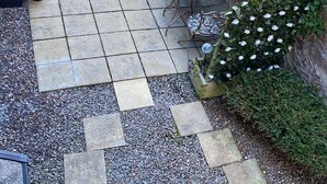 Una zona de pati amb una banca de fusta, una taula rodona petita i plantes en testos.