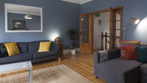 Una sala moderna con un sofá gris, una mesa de centro blanca y suelo de madera.