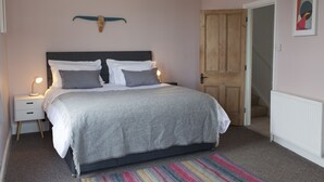 Un dormitorio con cama, mesitas de noche, una puerta de madera y un tapete colorido.