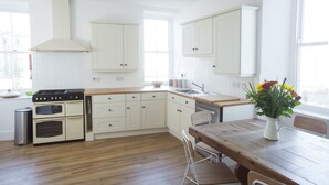 Una cocina con armarios blancos, encimera de madera y un comedor con mesa y sillas.