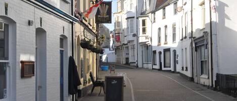 A narrow street with white buildings, a sign for 'Prince of Wales', and a blackboard with 'Carling' written on it.