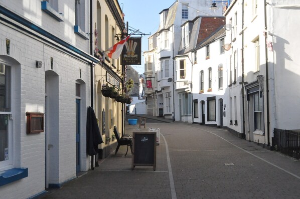 A narrow street with white buildings, a sign for 'Prince of Wales', and a blackboard with 'Carling' written on it. - The Salt House (Ilfracombe)