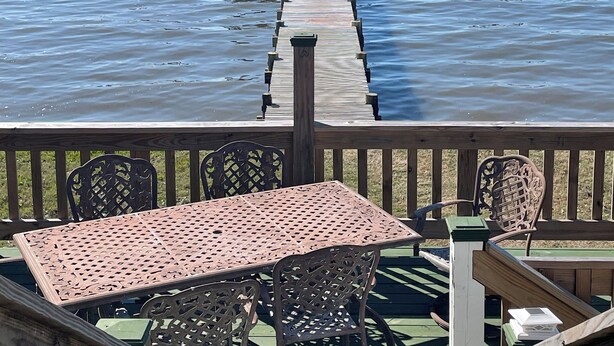A wooden deck with a table and chairs, leading to a pier with two gazebos over the water. - Waterfront Home with Dock! (Fairhope)