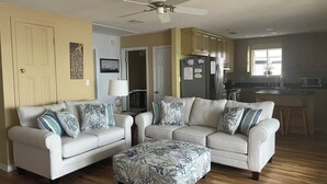 A living room with two sofas, a coffee table, a ceiling fan, and a kitchen in the background. - Waterfront Home with Dock! (Fairhope)