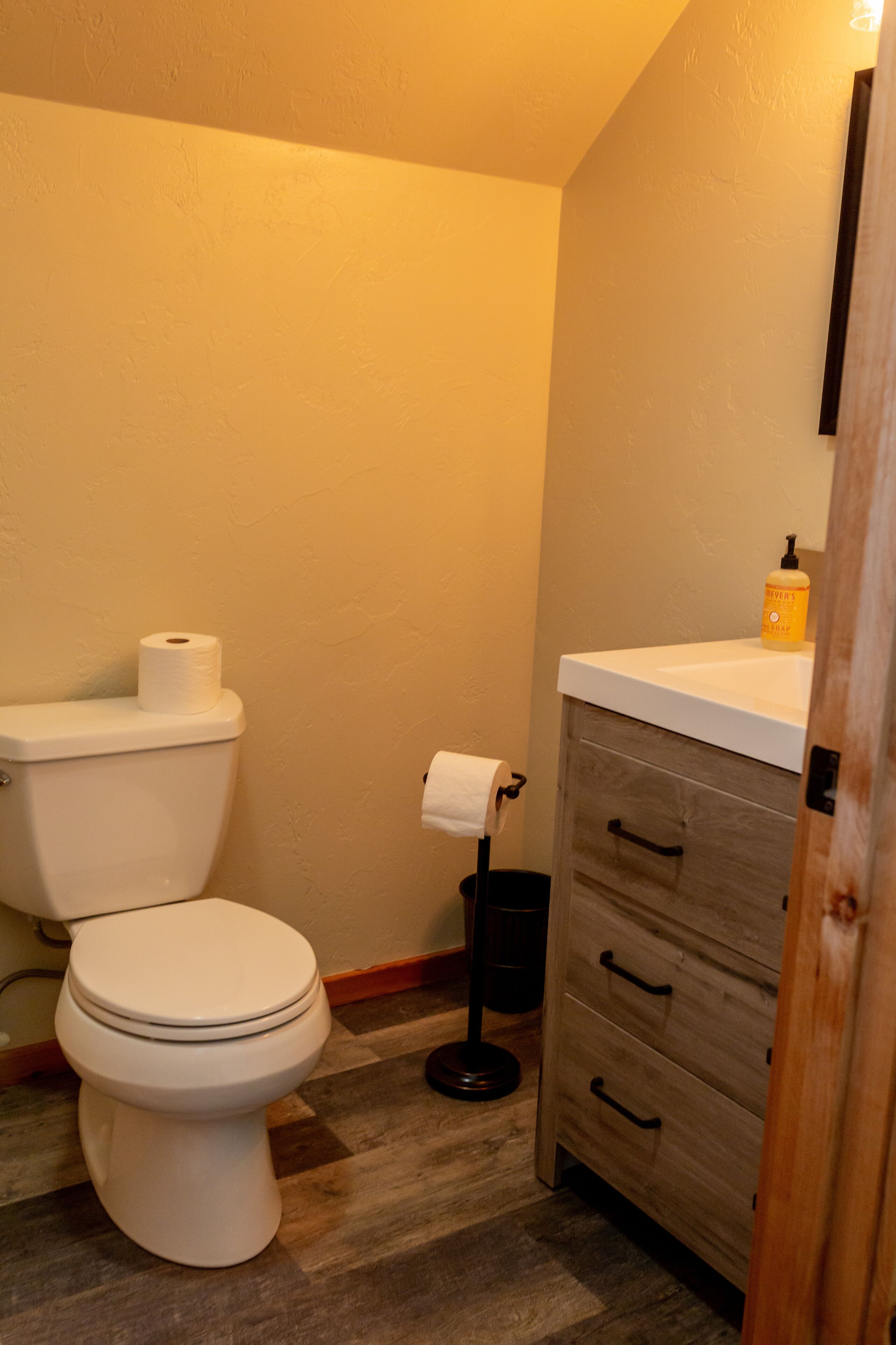 A bathroom with a toilet, a sink, and a wooden cabinet.