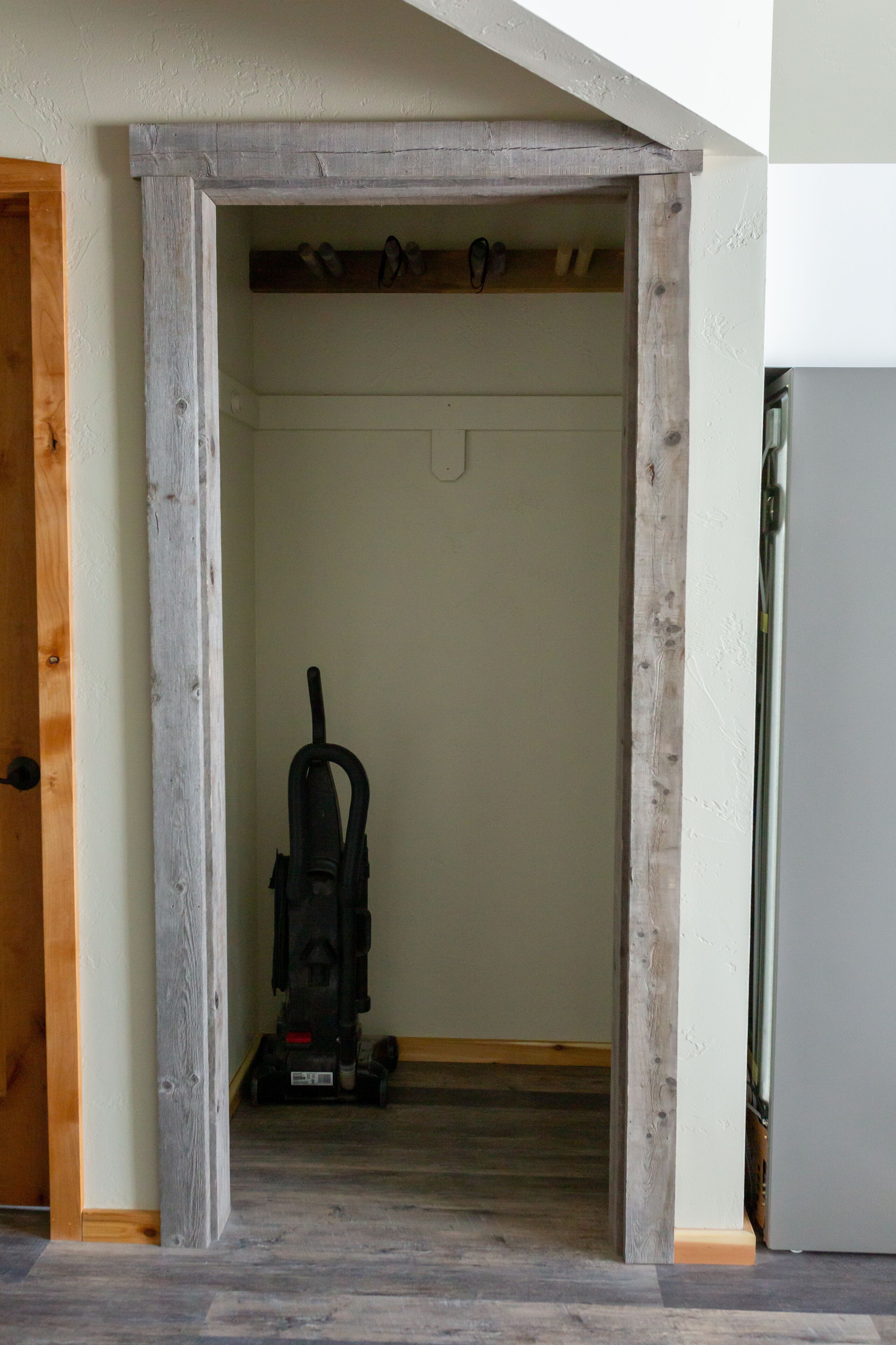 A narrow hallway with a wooden door frame, a vacuum cleaner, and a refrigerator.