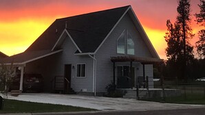 Une maison à deux étages avec un toit à pignon, une véranda et un garage apparent.