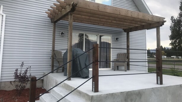 Une terrasse couverte avec des sièges d’extérieur, un escalier en béton et une vue sur une chaîne de montagnes.