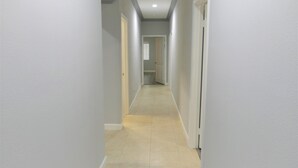 A narrow hallway with light gray walls and a light beige tiled floor. - Spacious Home* 7 minutes to Disneyland (Anaheim)