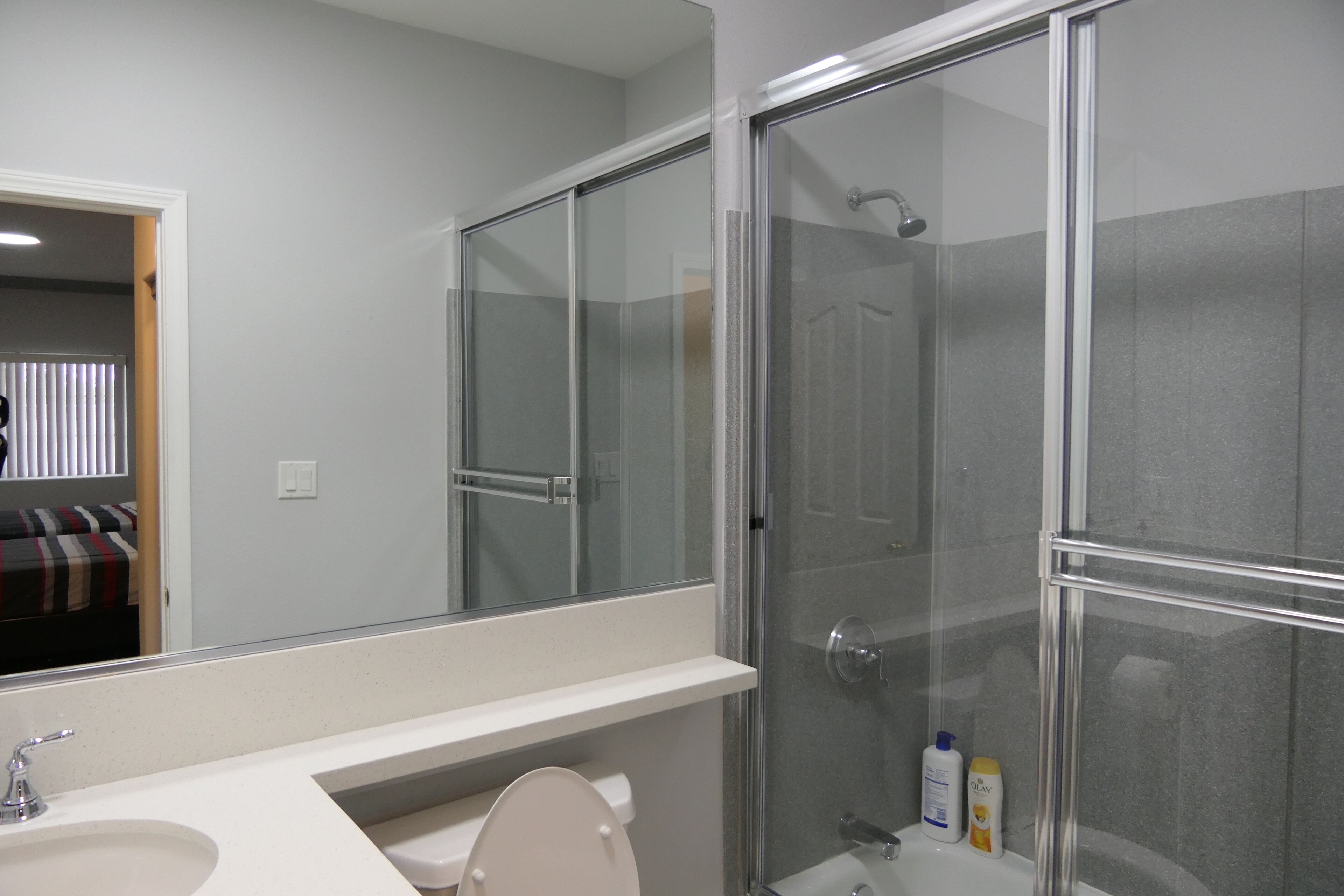 Une salle de bain avec une douche à parois de verre, un lavabo blanc et des toilettes.