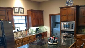 A spacious kitchen with a large island, wooden cabinets, and modern appliances including a refrigerator, microwave, and dishwasher. - Landry Ranch Vacation Home - Close to the Franklin Ranch Baseball Complex! (Franklin)