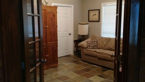An open doorway leading to a living room with a beige couch, a wooden cabinet, and a ceiling fan. - Landry Ranch Vacation Home - Close to the Franklin Ranch Baseball Complex! (Franklin)