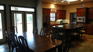 A spacious kitchen with wooden cabinets, a large island, and a dining area with chairs. - Landry Ranch Vacation Home - Close to the Franklin Ranch Baseball Complex! (Franklin)
