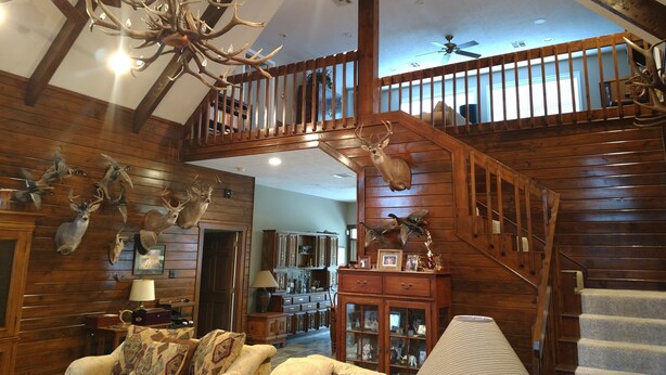 A spacious living room with a high ceiling, wooden beams, a chandelier, and a staircase with a railing. - Landry Ranch Vacation Home - Close to the Franklin Ranch Baseball Complex! (Franklin)