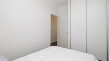 A bedroom with a bed, a wardrobe, and a door leading to another room.