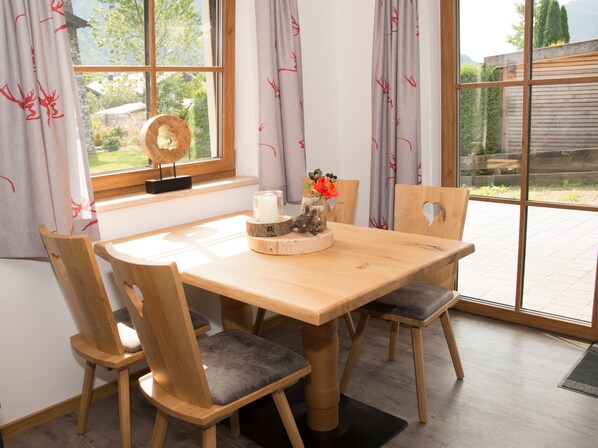 A wooden dining table with four chairs, a candle, and a decorative centerpiece.