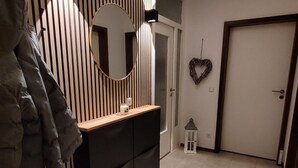 A modern interior with a striped wall, a round mirror, a wooden console, a heart-shaped decoration, and a door. - °Ferienwohnung Hedy mit 1 sep. Schlafzimmer, Südterrasse, 55 qm (Prien am Chiemsee)