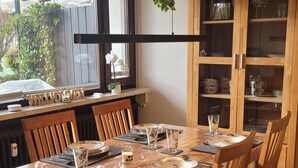 A dining area with a wooden table set for six, surrounded by chairs, with a view of the outdoors through a window. - °Ferienwohnung Hedy mit 1 sep. Schlafzimmer, Südterrasse, 55 qm (Prien am Chiemsee)