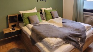 A modern bedroom with a wooden bed, green walls, and a ceiling light fixture. - °Ferienwohnung Hedy mit 1 sep. Schlafzimmer, Südterrasse, 55 qm (Prien am Chiemsee)