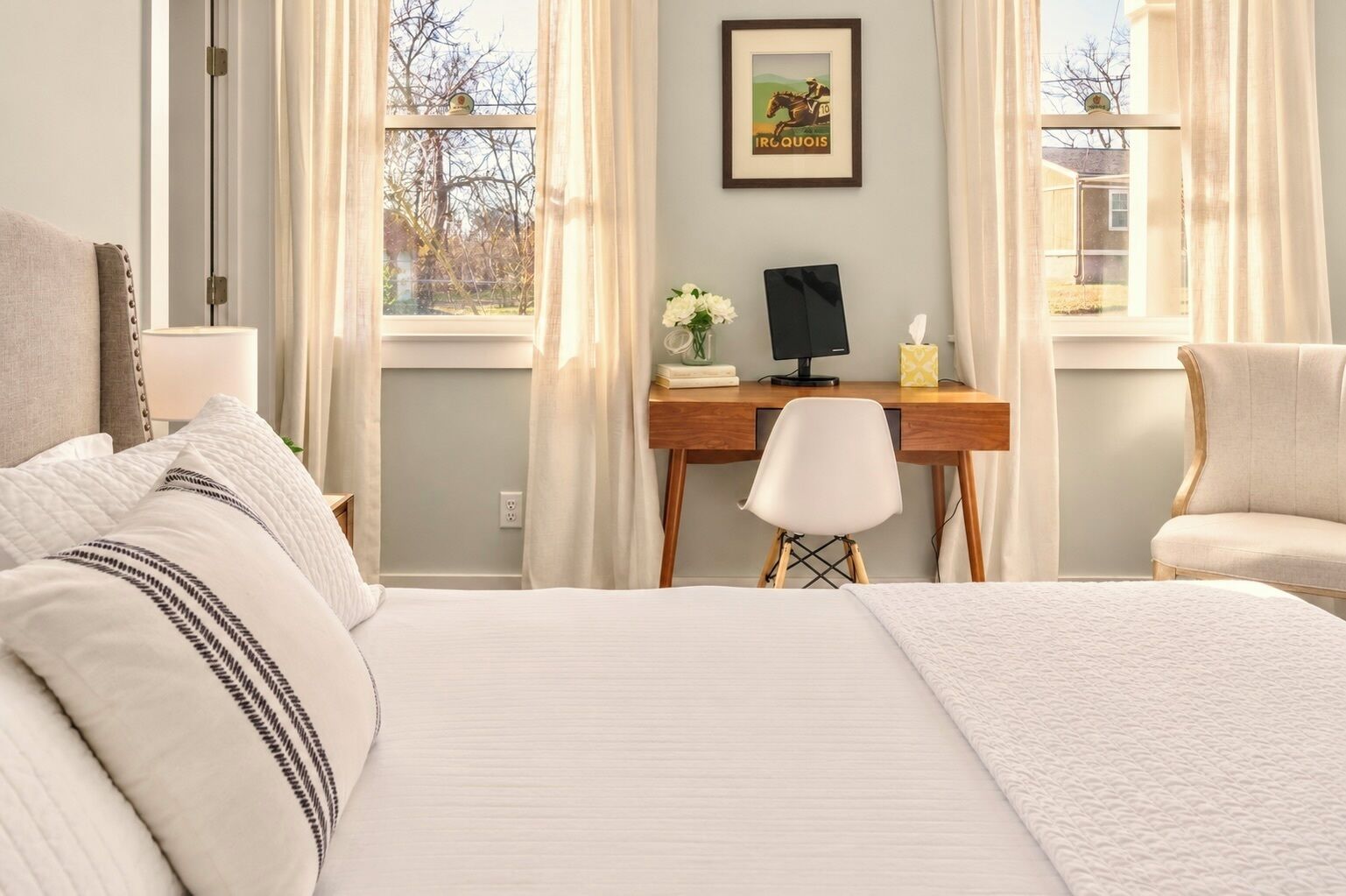 Een hotelkamer met een groot bed, een bureau, een stoel en een raam met gordijnen.