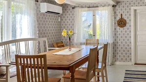 Un comedor con mesa y sillas de madera, un florero con flores y papel tapiz estampado.