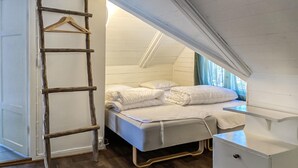 Un dormitorio compacto estilo loft con una cama, una escalera de madera y un escritorio pequeño.