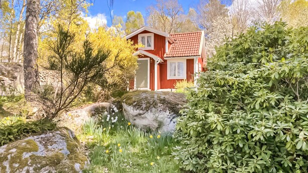 Una casa roja con techo de tejas, rodeada de árboles y follaje.