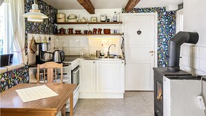 Una cocina con armarios blancos, una mesa de madera, una estufa y una pared decorativa.