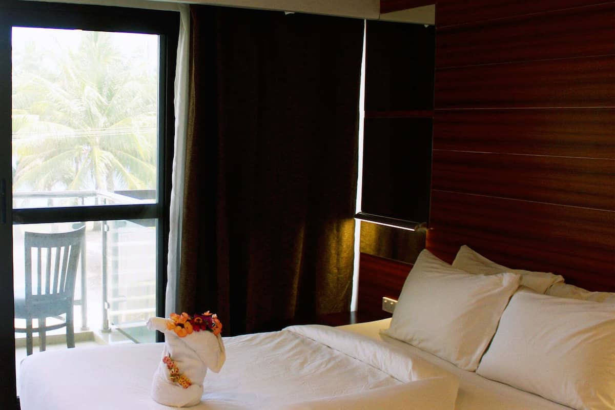 A hotel room with a bed, a chair, and a window with curtains.