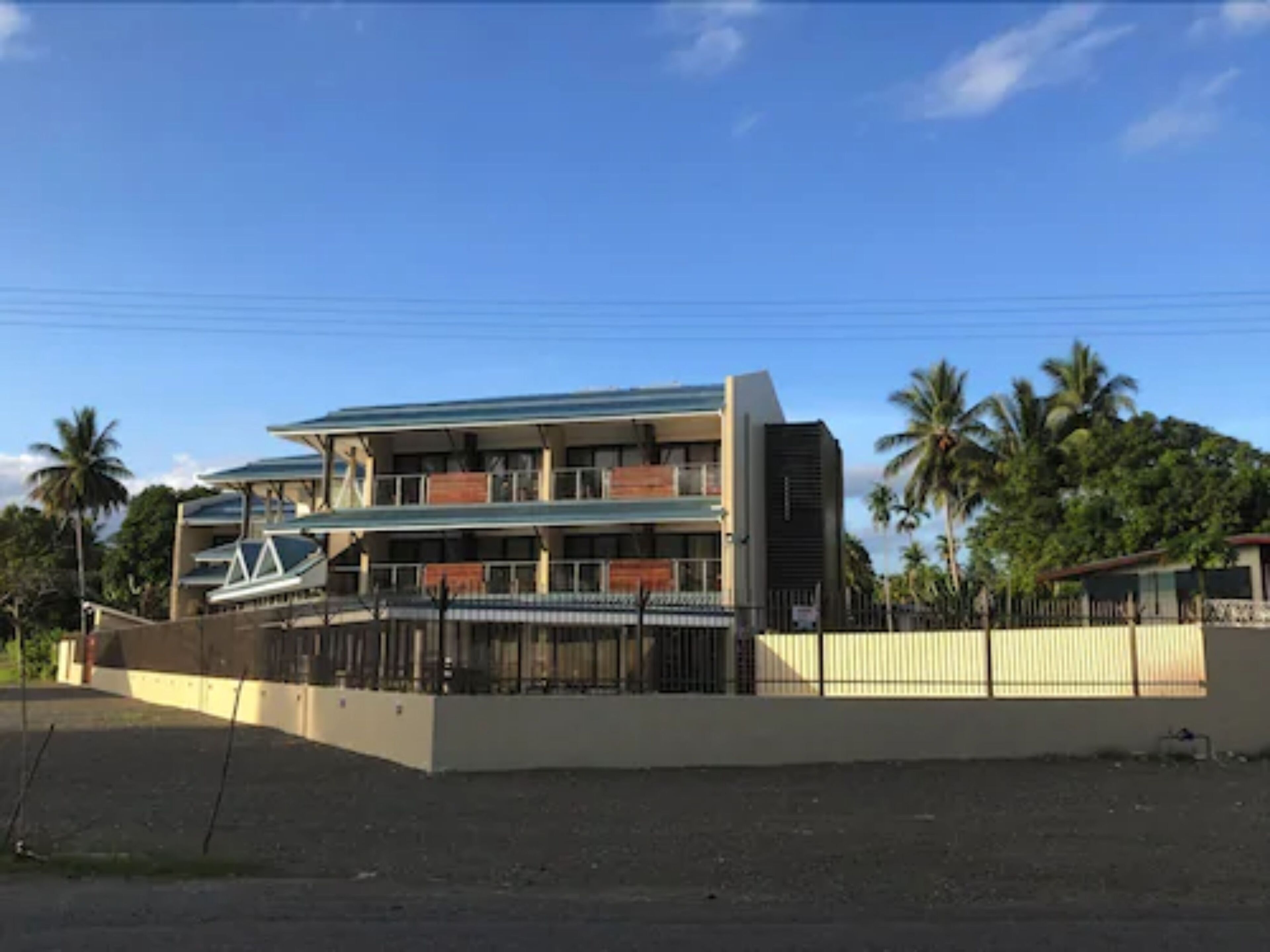 A multi-story building with a flat roof, balconies, and a gated entrance.