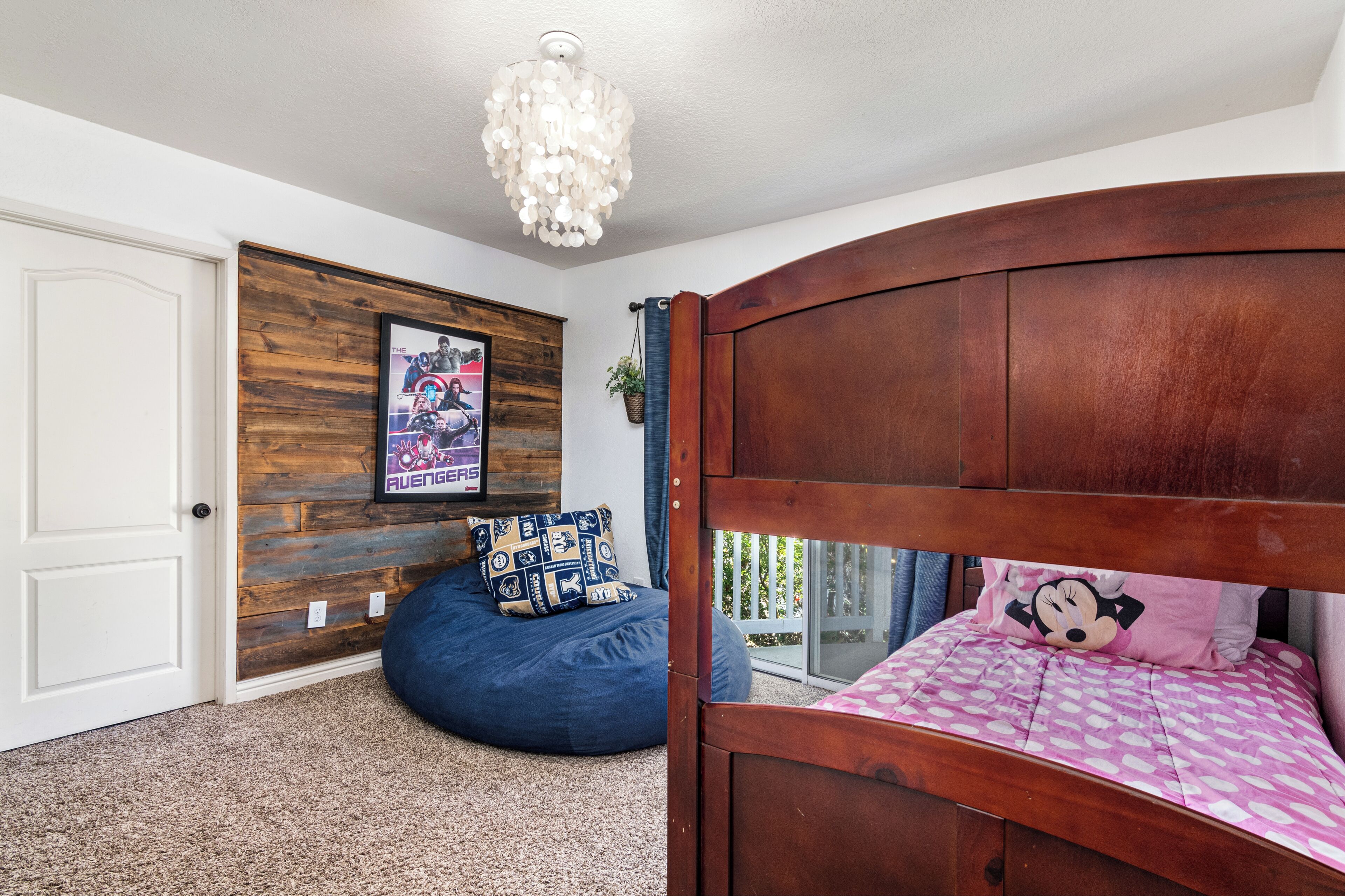 Un dormitorio con cabecera de madera, un sillón de peluche, un cartel en la pared y una ventana con vistas.