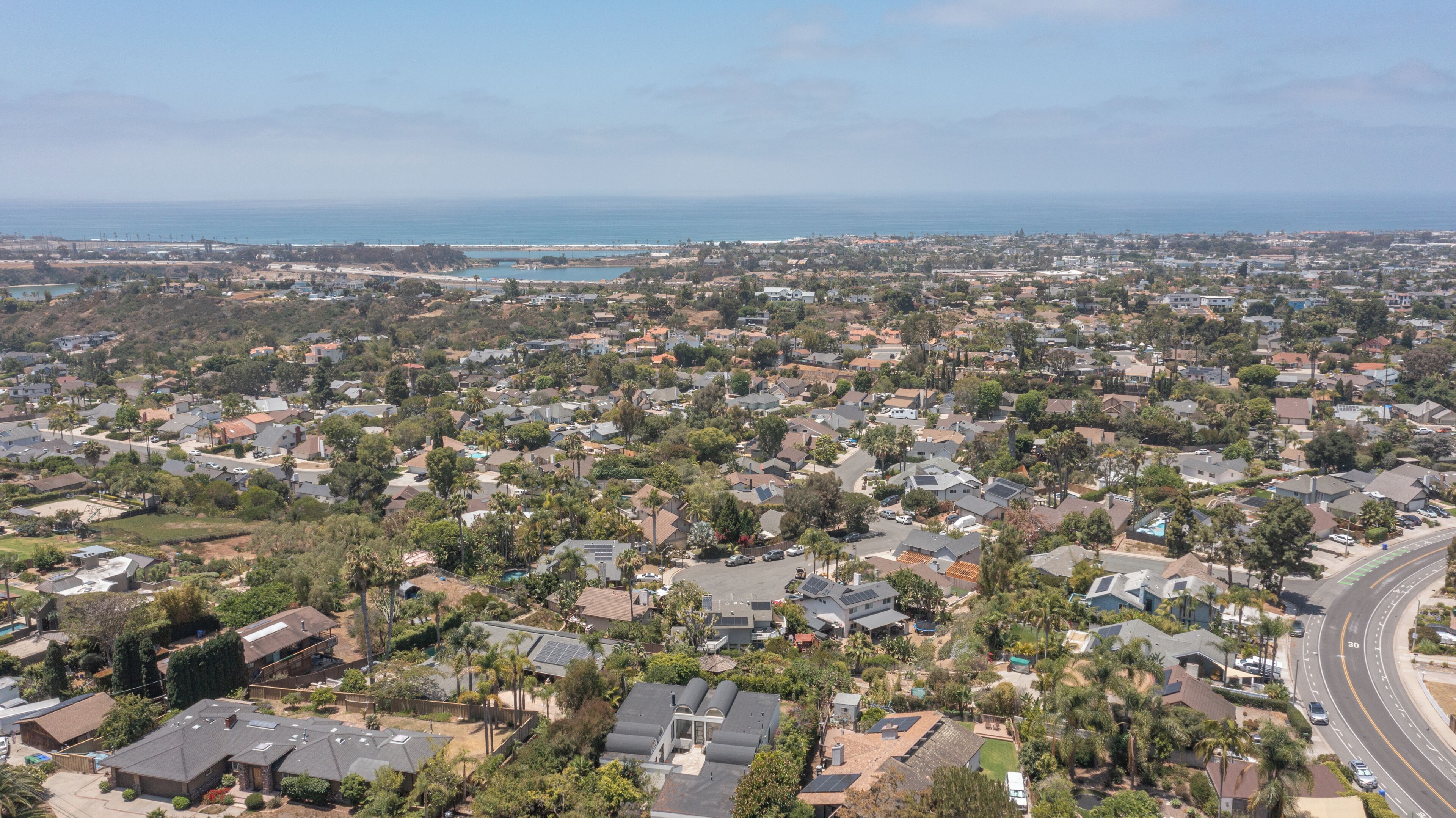 A residential area with houses, roads, and a coastline.