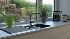 A kitchen with a modern sink, a coffee maker, and a potted plant. - Dream vacation in the Allgäu in the eco house with a clear view of nature (Isny)