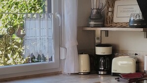 Een keuken met een raam, een koffiezetapparaat, een broodrooster en een blender op het aanrecht.