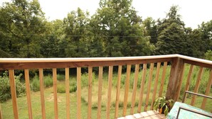 A wooden deck with a checkered floor, a metal railing, and a bench.
