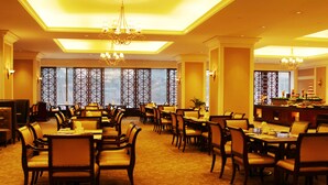 En hotels restaurant med flere borde og stole, lysekroner og store vinduer med udsigt.