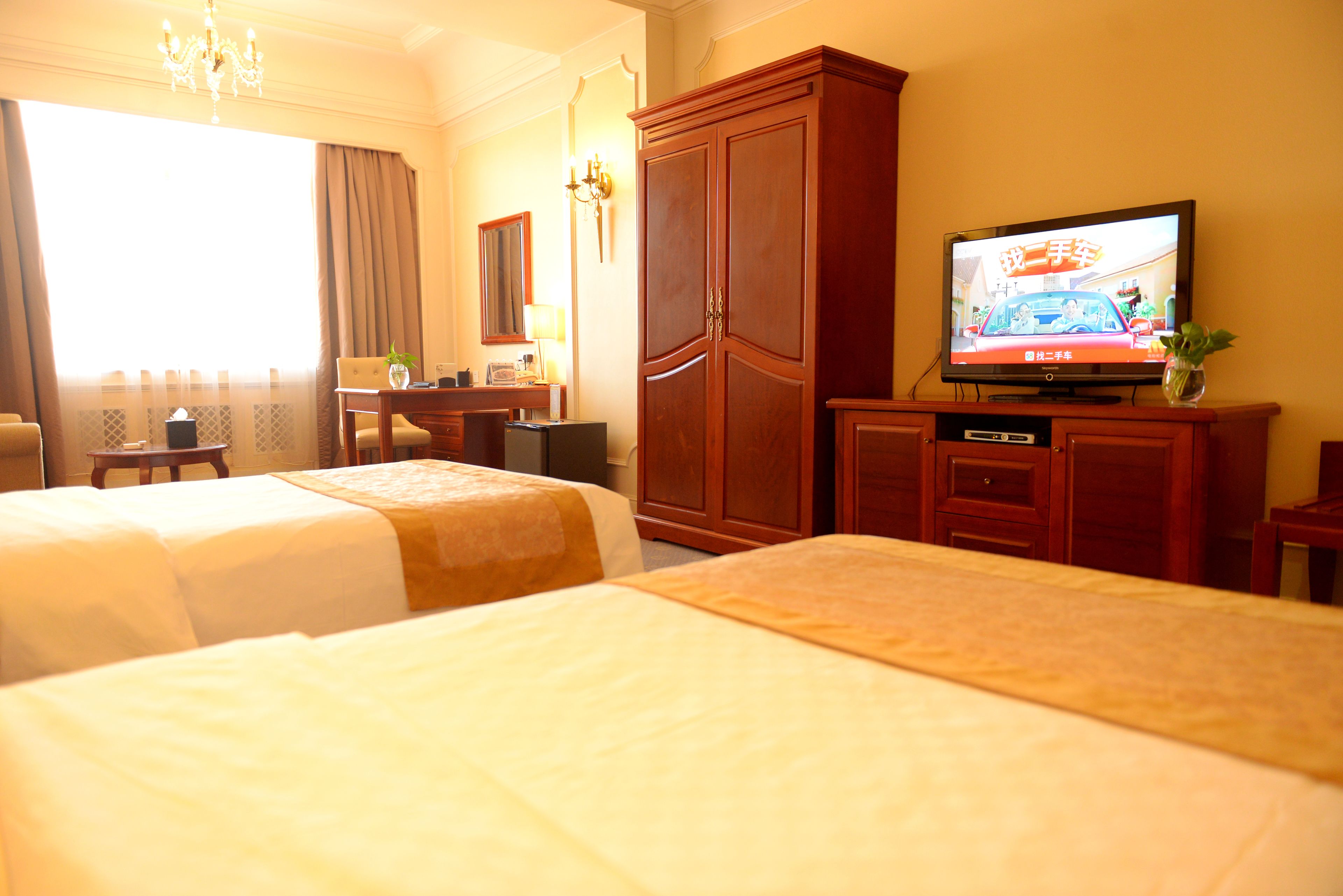 A hotel room with two beds, a television, a desk, and a wardrobe.