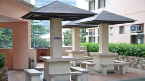 Outdoor seating with umbrellas, a stone wall, and a smoke-free sign. - A Homey Place Manila, 1 Bedroom (Manila)