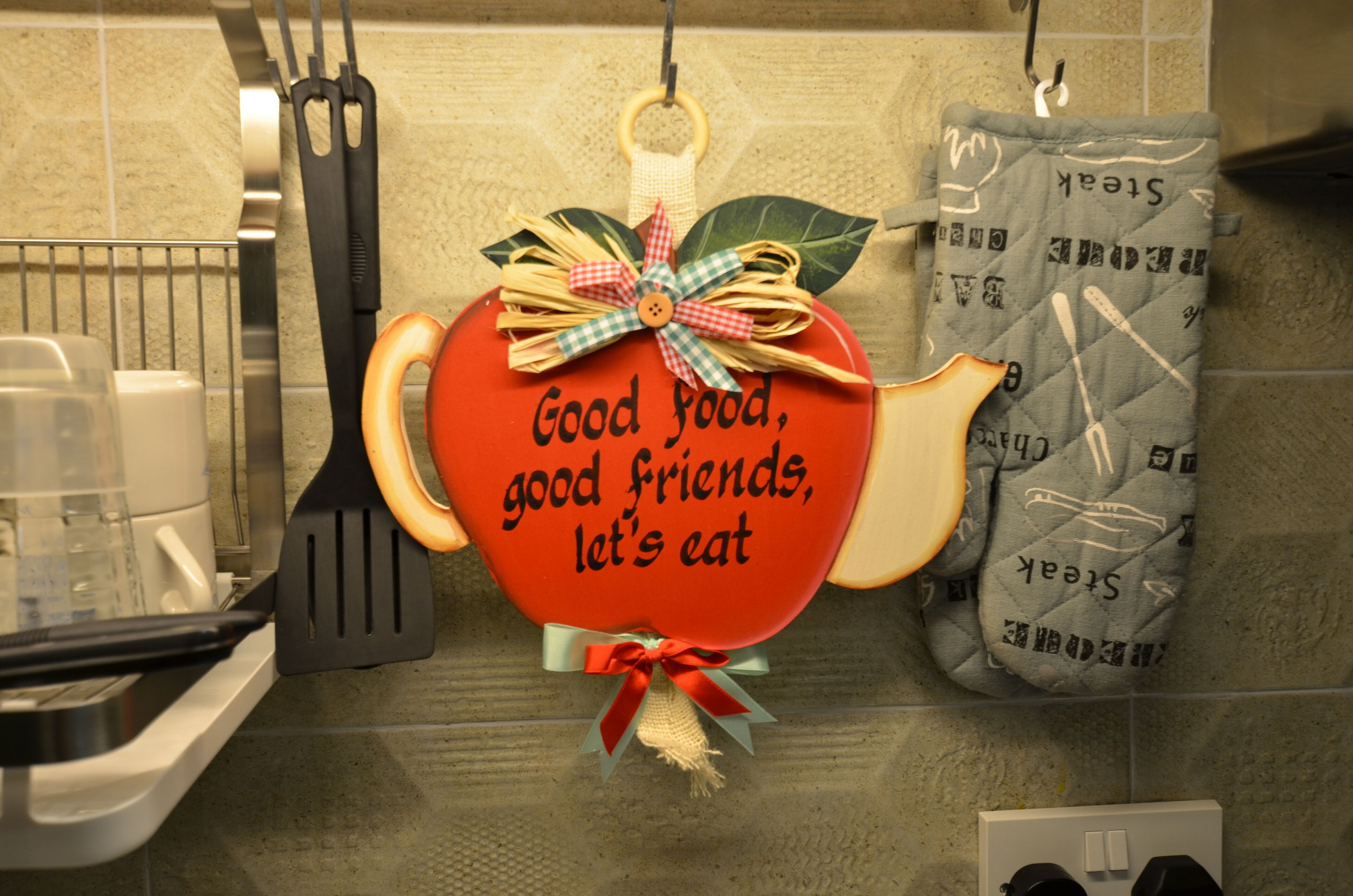 A kitchen with a heart-shaped sign that reads "Good food, good friends, let's eat."