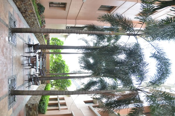 A courtyard with palm trees, outdoor seating, and a building facade.