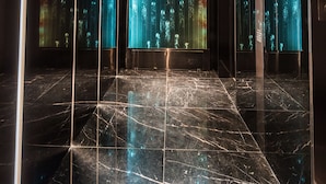 An elevator interior with a digital display on the walls and a marble floor.