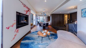 A modern hotel lobby with a flat-screen TV, a dining area, and a reception desk.