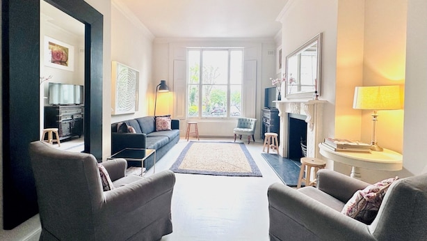 A modern living room with a sofa, armchairs, a fireplace, and a large window. - Notting Hill Newly Decorated 3-Bedrooms with large Private Garden (London)