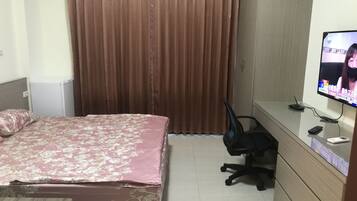 Una habitación de hotel con cama, escritorio con computadora, silla y televisor.