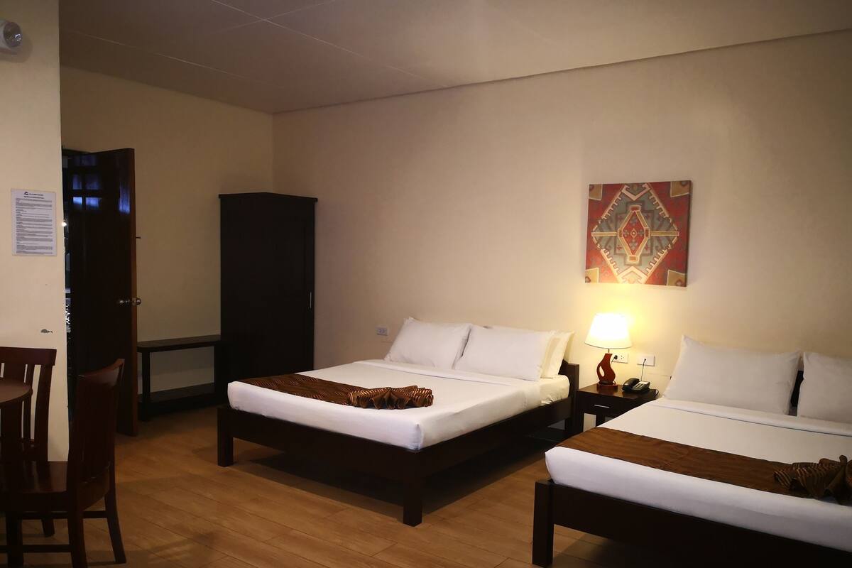 Une chambre d’hôtel avec deux lits, un bureau et une chaise.