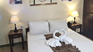 Quarto de hotel com uma cama, duas mesinhas de cabeceira e um quadro de parede com uma cena de praia.