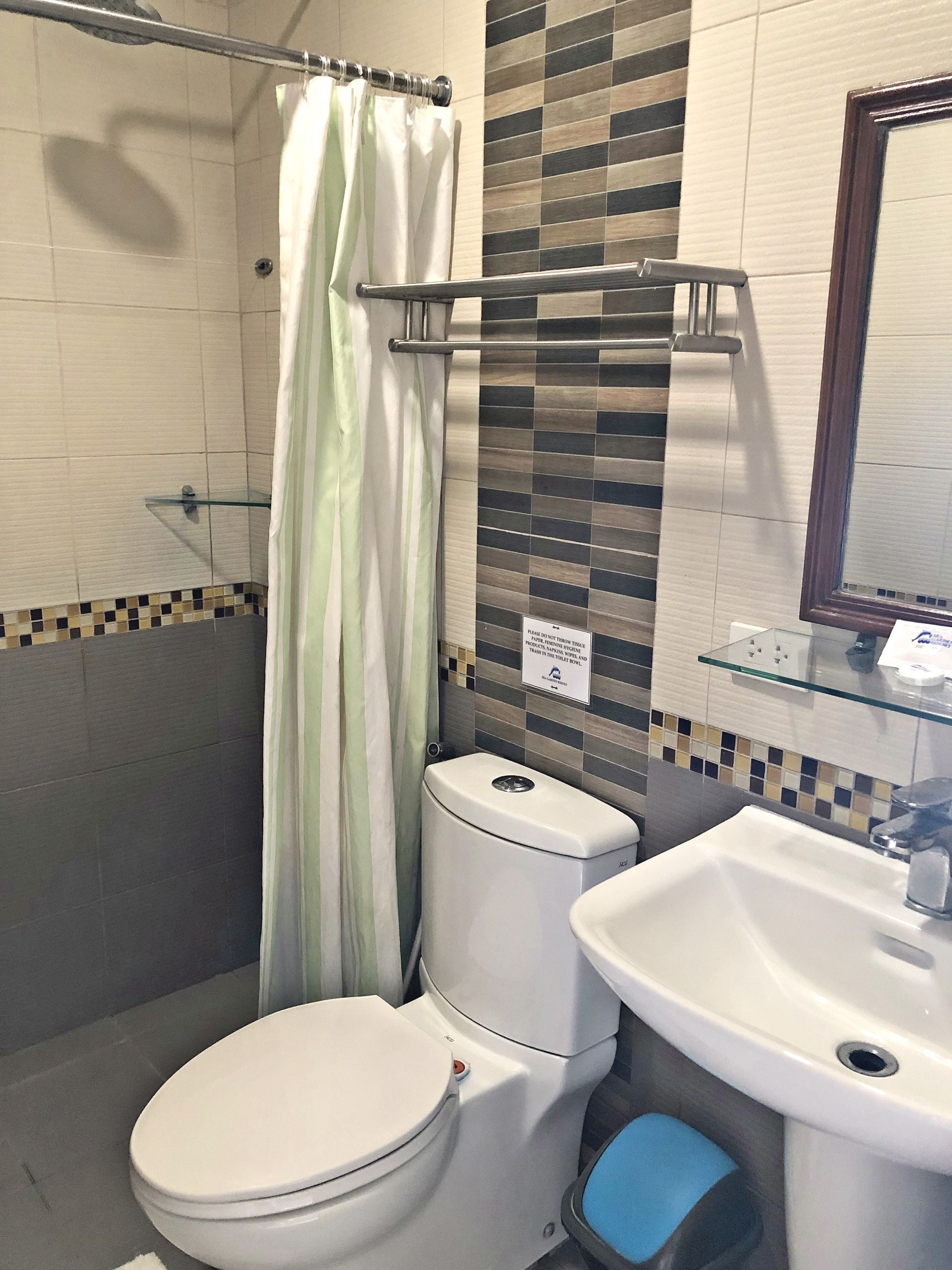 Un bagno con un WC, cabina doccia in vetro, lavandino e specchio.